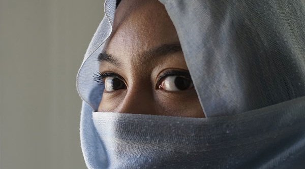 Eine Frau verhüllt ihr Gesicht mit einem blauen Schleier