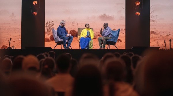 Markus Rhode sitzt mit Abdi und Kawser auf der Bühne und spricht