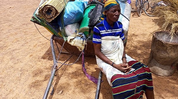 Eine afrikanische Frau sitzt auf dem Boden mit dem Rücken an einen Stapel Gepäck gelehnt