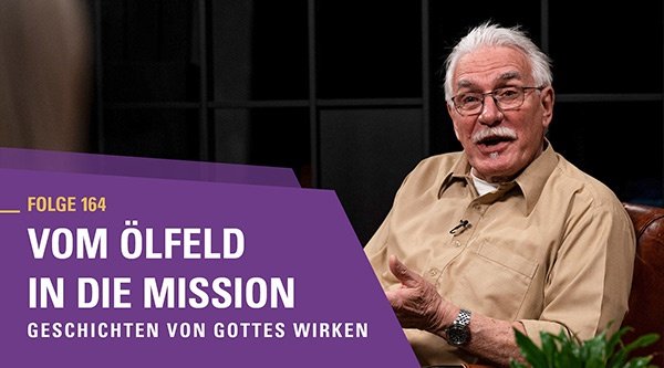 Ein älterer Mann mit Schnurrbart, Brille und beigem Hemd spricht enthusiastisch in einem Interview