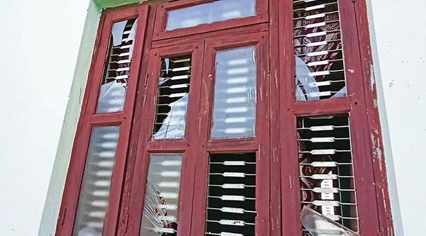 Ein rotes Fenster mit eingeschlagenen Scheiben.