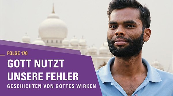 Mann aus Indien mit einer Moschee im Hintergrund schaut lächelnd in die Kamera.