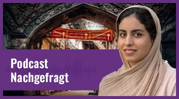 Eine iranische junge Frau mit hellem Schleier und Oberteil lächelt vor einer mit Stromkabeln und Rundbögen befüllten Straße