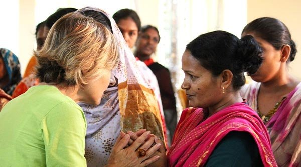 Hellhäutige Frau umschließt die Hände einer indischen Frau. 