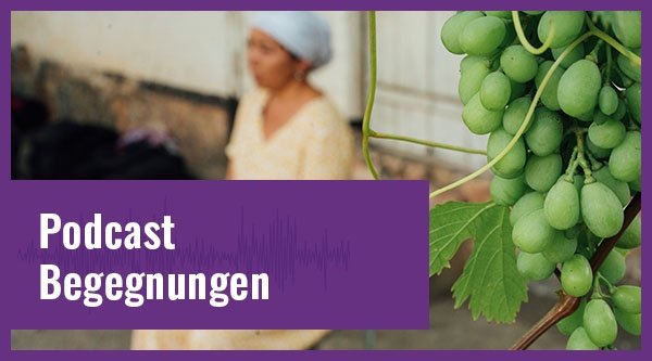 Eine Frau sitzt betend auf einer Stufe im Vordergrund eine Weinrebe