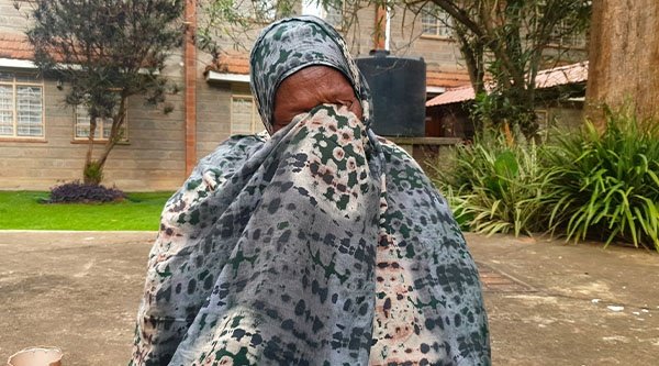 Eine afrikanische Frau hält ein Tuch vor ihr Gesicht