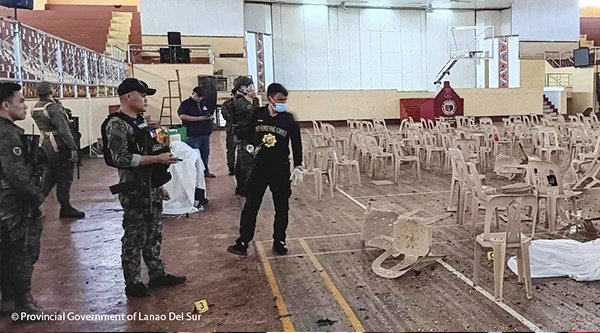 Einsatzkräfte stehen zwischen Trümmern in einer Turnhalle