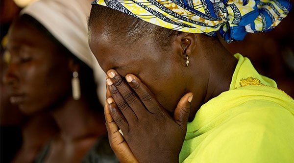 Nigerianische Frau hat ihr Gesicht in ihren Händen vergraben