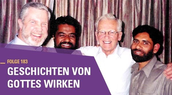 Vier Männer stehen dicht beieinander und lachen