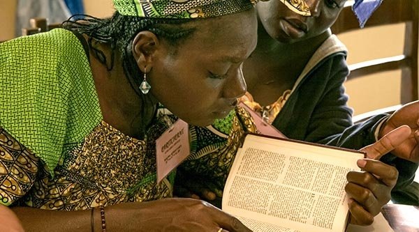 Eine junge Frau beugt sich über eine Bibel und liest darin