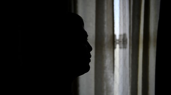 Die dunklen Umrisse einer Person vor einem zugehängten Fenster