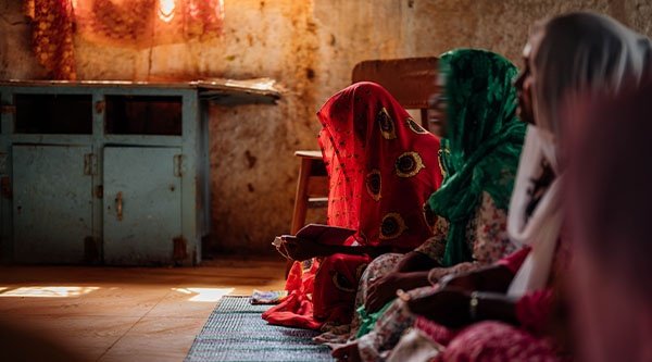 Drei indische Christinnen beten in einem abgedunkeltem Raum
