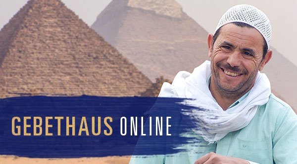 Ein Mann steht vor zwei Pyramiden und lacht