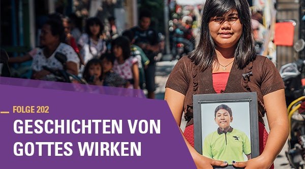 Eine indonesische Frau hält das Bild ihres verstorbenen Sohnes in der Hand. Sie steht im Freien und wird von der Sonne angestrahlt. Im Hintergrund sind verschwommen mehrere Menschen zu sehen.