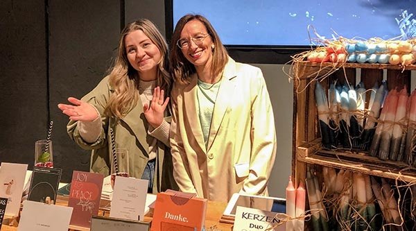 Zwei Frauen stehen an einem Stand mit Kerzen