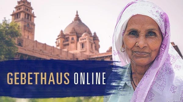 Poträt einer älteren Frau vor einem indischen Gebäude