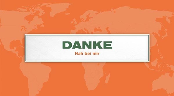 Auf einem orangenen Hintergrund steht ein Schild mit dem Titel in grün: Danke