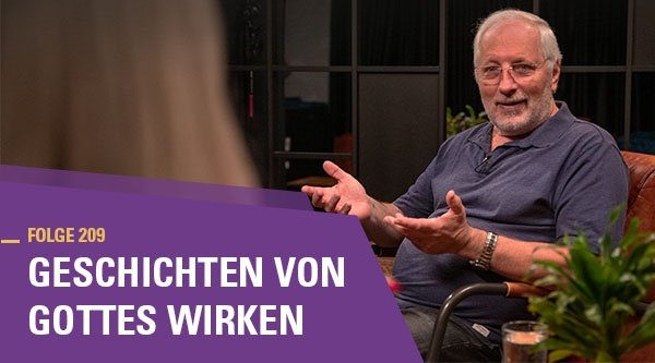 Ein älterer Mann sitzt in einem Sessel und gestikuliert mit seinen Händen