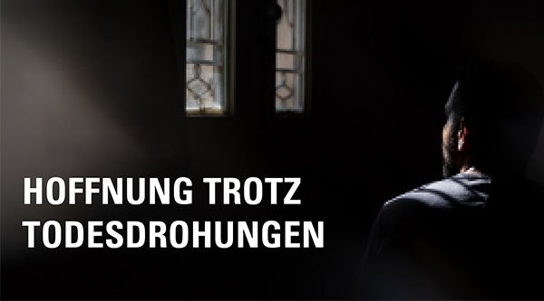 Eine Person sitzt in Dunkelheit und wird durch ein Fenster angestrahlt