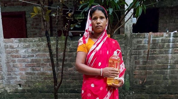 Eine Frau mit roter Kleidung hält eine Flasche in den Händen und schaut traurig