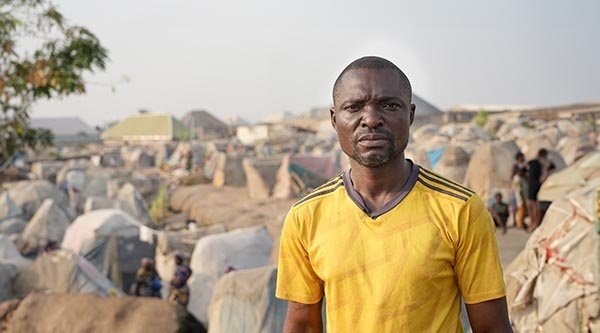 Pastor Barnabas steht vor einem Flüchtlingscamp in Nigeria