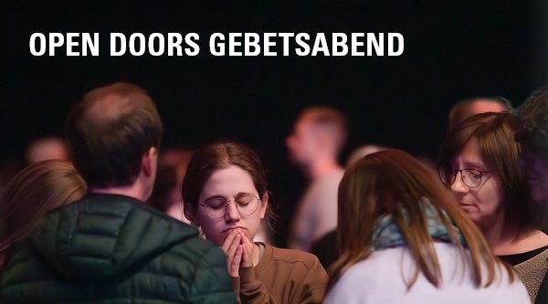 Eine Gruppe von Menschen gemischten Alters steht zusammen im Gebet für verfolgte Christen
