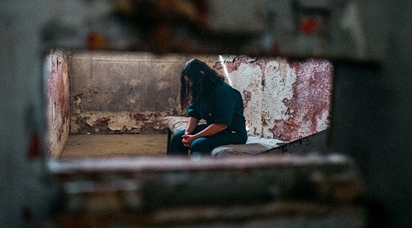 Eine Frau sitzt in einer kahlen Zelle