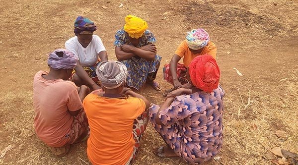 Sechst Frauen sitzen im Kreis auf dem Boden beieinander