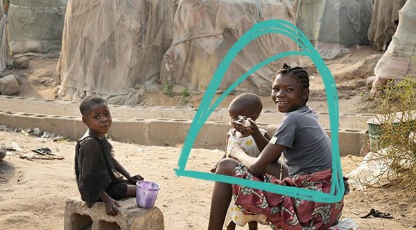 Kinder sitzen auf provisorischen Stühlen in einem afrikanischem Flüchtlingscamp
