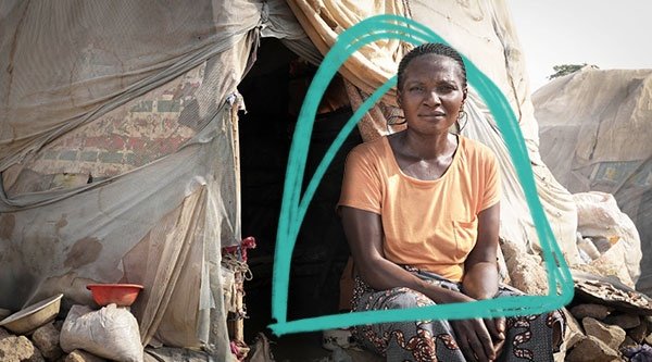 Eine afrikanische Frau sitzt vor einem Zelt in einem Flüchtlingscamp.