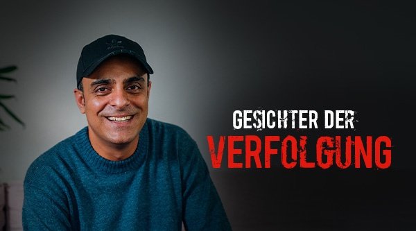 Ein Mann mit einer Kappe und blauem Langarmshirt vor einem neutralen grauen Hintergrund
