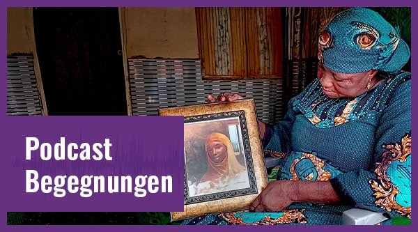 Eine Frau mit blauer Kleidung hält ein Bilderrahmen in den Händen auf dem eine junge Frau zu sehen ist