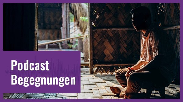 Ein Mann sitzt in einer dunklen Hütte.