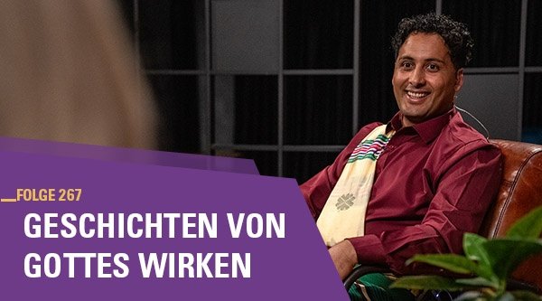 Ein Mann sitzt auf einem braunen Ledersessel und wird interviewt.