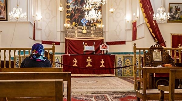 Eine Frau mit einer Kopfbedeckung sitzt in einer Kirche