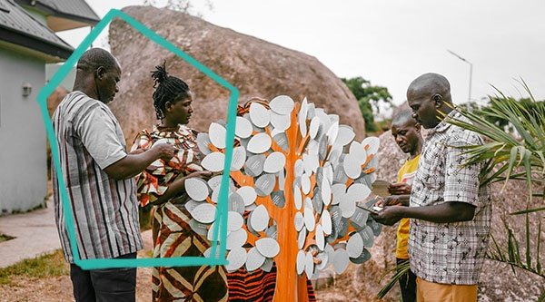 Afrikanische Christen stehen vor dem Baum der Ermutigung und lesen Ermutigungsbotschaften.