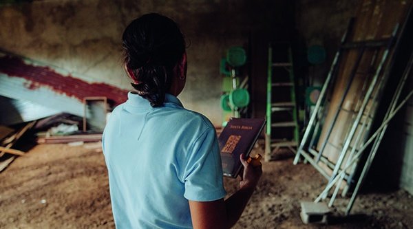 Eine Frau hält eine Bibel in der Hand und steht in einem Gebäude