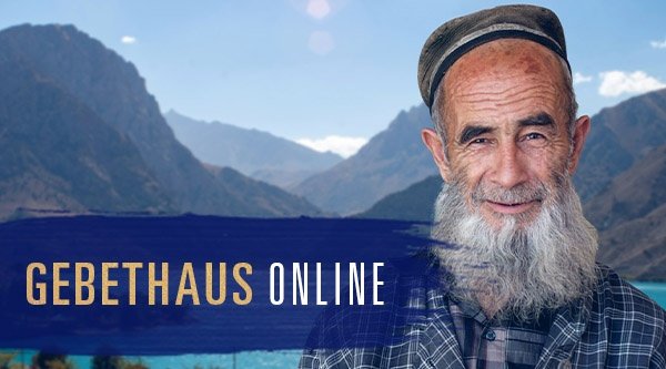 Ein Mann aus Tadschikistan steht vor einer Berglandschaft und einem Fluss.