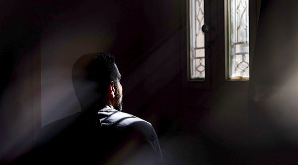 Ein Mann in einem dunklen Raum schaut aus einem Fenster