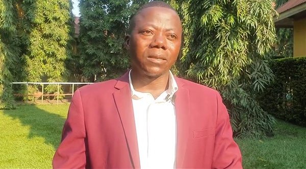 Ein Mann mit Anzug steht vor der Kamera