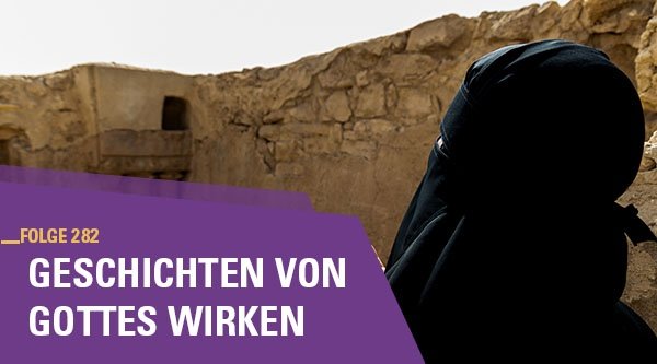 Eine verschleierte Frau betet vor einem zerfallenen Gebäude