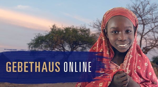 Ein afrikanisches Mädchen steht vor einem Dorf und lächelt