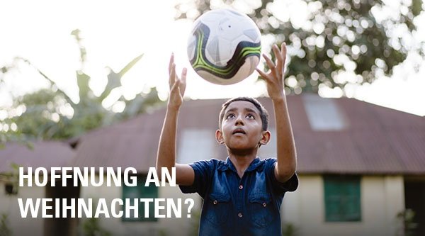 Ein Junge spielt mit einem Ball vor einem Haus