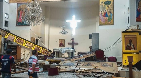 Menschen stehen in einer zerstörten Kirche