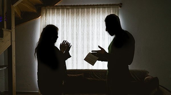 Ein Mann und eine Frau reden in einem dunklen Raum mit einem Buch in der Hand