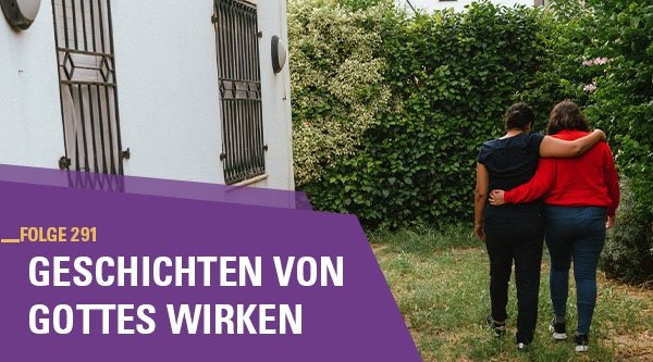 Zwei Frauen laufen Arm in Arm durch einen Garten