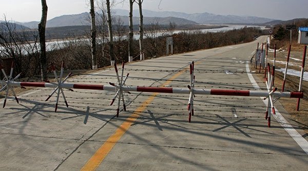 Eine Schranke mit Stacheldraht versperrt eine Bergstraße