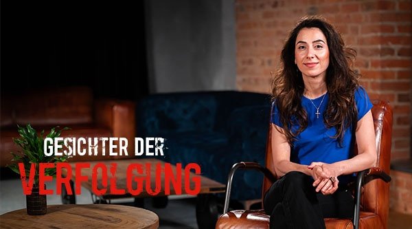 Eine Frau sitzt auf einem Sessel und lächelt in die Kamera