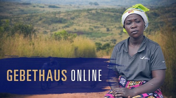 Eine Frau sitzt vor einer hügeligen Landschaft