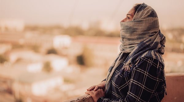 Eine verschleierte Frau blickt auf eine Stadt